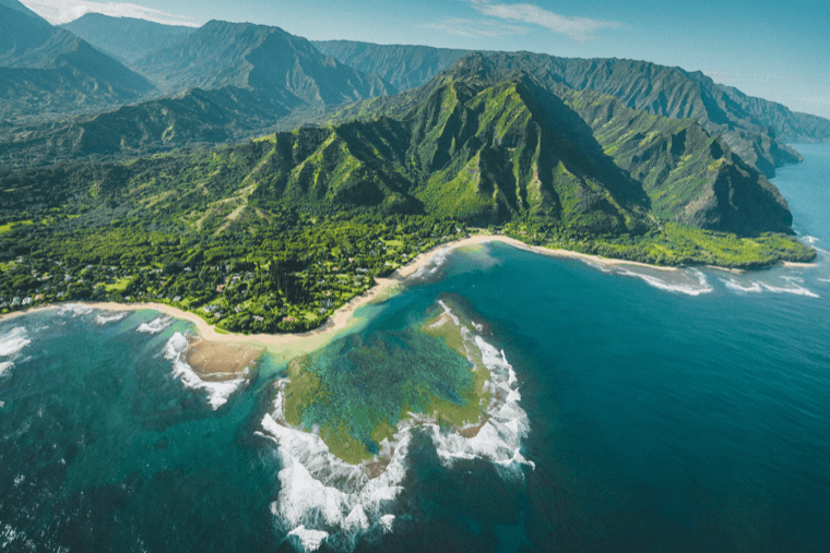 Aerial view of the green Nā Pali Coast meeting the Pacific Ocean